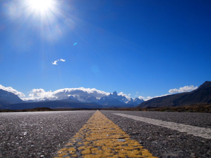 open empty road with blue skies and mountain in the distance