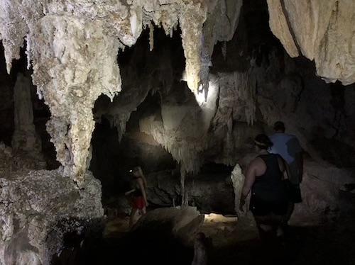 people walking inside dark cave in thailand with headlamps lighting the way