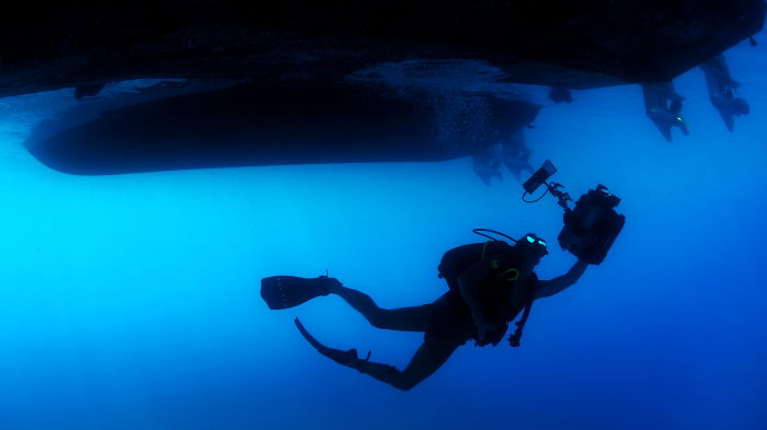 a diver with a technical diving certification filming under a liveaboard boat