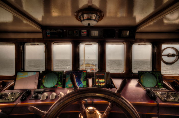inside of a scuba diving liveaboard boat with a view of the ocean and steering wheel