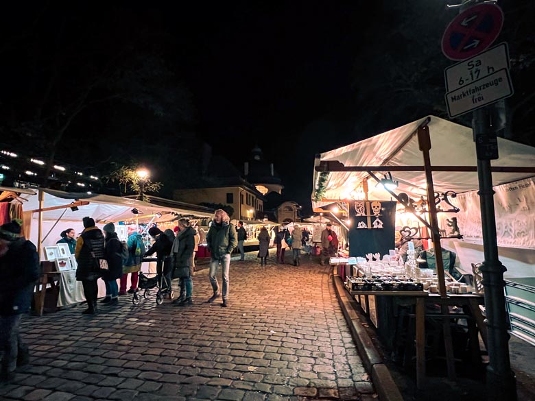 people walking past market stalls selling unique xmas gifts at an alternative christmas market in berlin