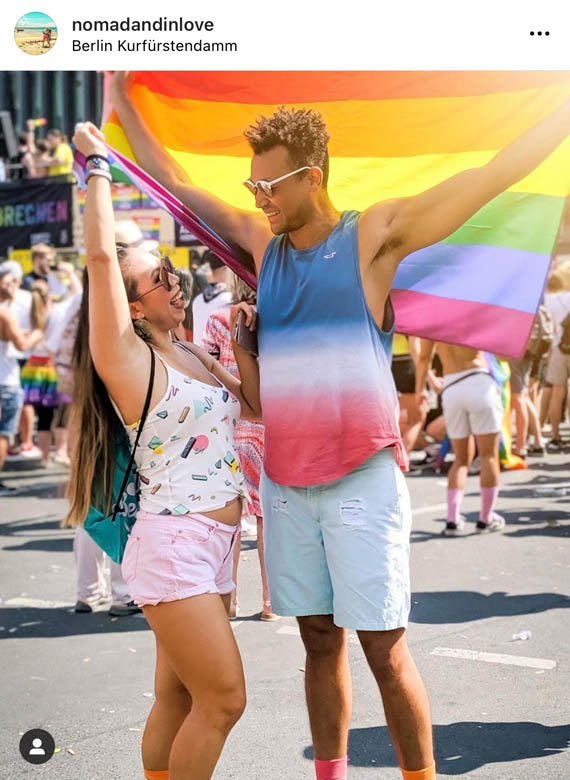 street photography of an interracial couple holding up a pride flag at berlin csd festival