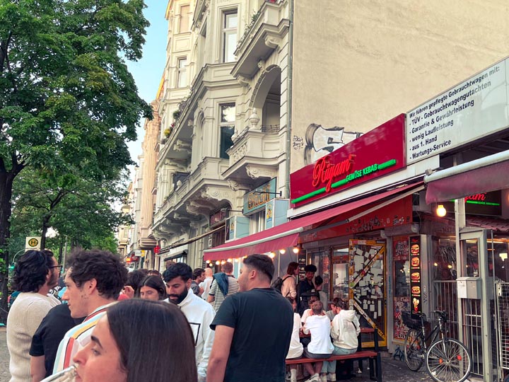 a long queue of people standing outside a local doner spot for cheap eats in berlin germany