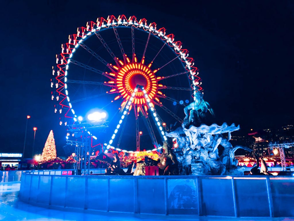 berliner wiehnachtszeit christmas market at rotes rathaus close to alexanderplatz in berlin with huge ferris wheel, skating rink and neptune fountain in the background