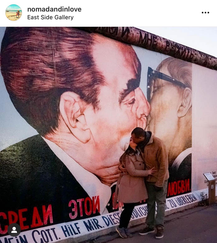 couple kissing in front of berlin famous kissing graffiti on east side gallery germany