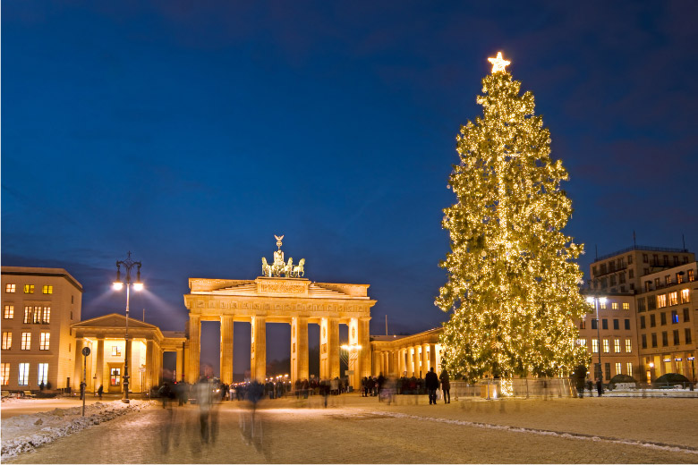 berlin brandenburg gate with a large christmas tree in front and people drinking gluhwein