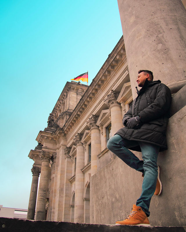a man leaning against the wall of the Berlin landmark Reichstag Building