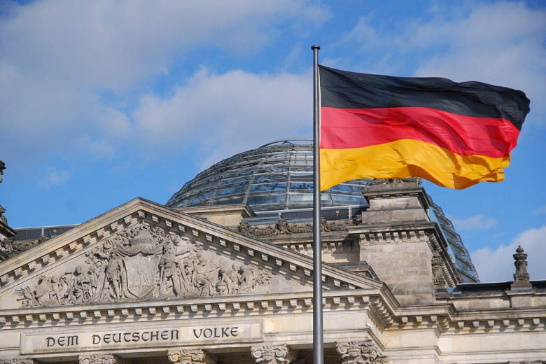 german red black and yellow flag in front of reichstag parliamentary building in berlin