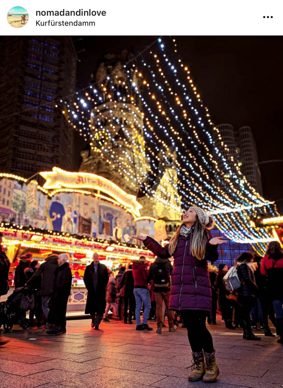 woman admiring fairylights at a popular german christmas market in berlin in front of Kaiser Wilhelm Memorial Church