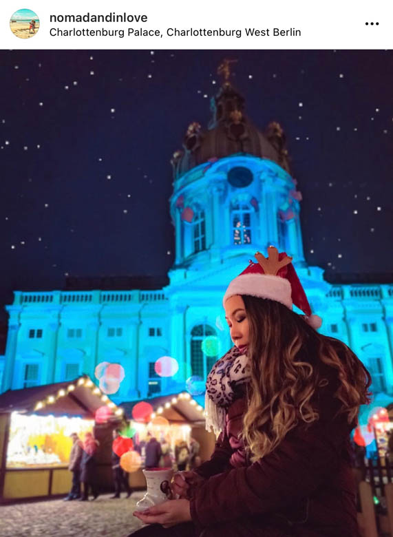 photography of a woman holding a christmas mug in front of charlottenburg christmas market in berlin