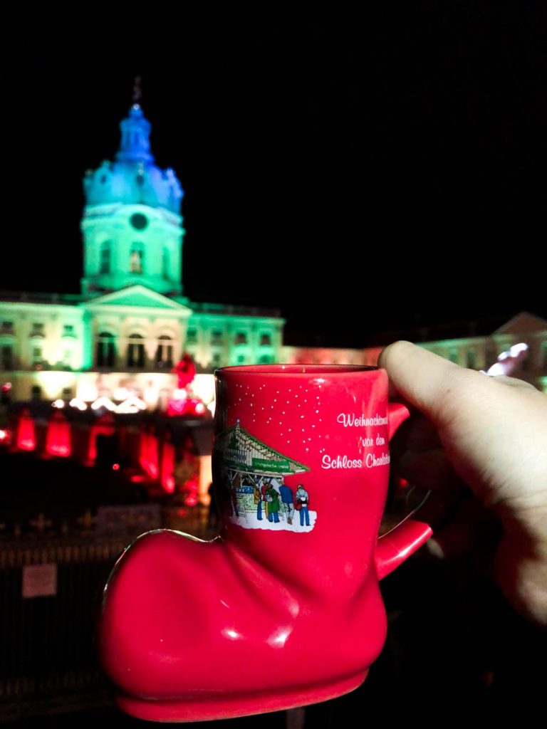 red christmas mug in a shape of a xmas stocking with charlottenburg palace lit up in the background