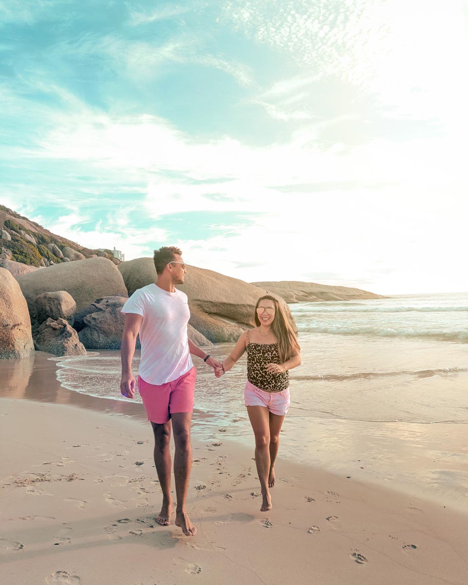 a couple running down llandudno beach in cape town at sunset