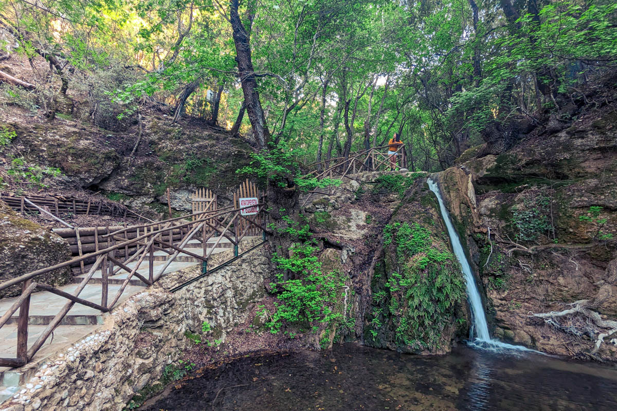 a woman standing above a waterfall in a dense forest at butterfly valley rhodes 