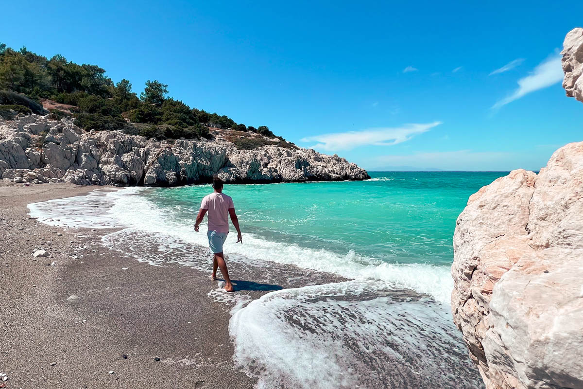 a man walking on a beautiful beach in west rhodes greece