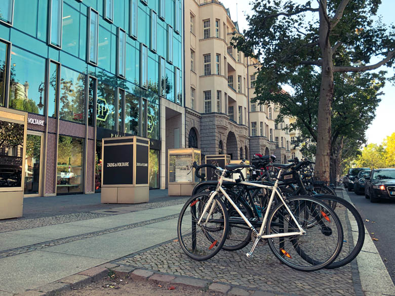 a row of parked bicycles on the pavement next to the road in kurfürstendamm germany