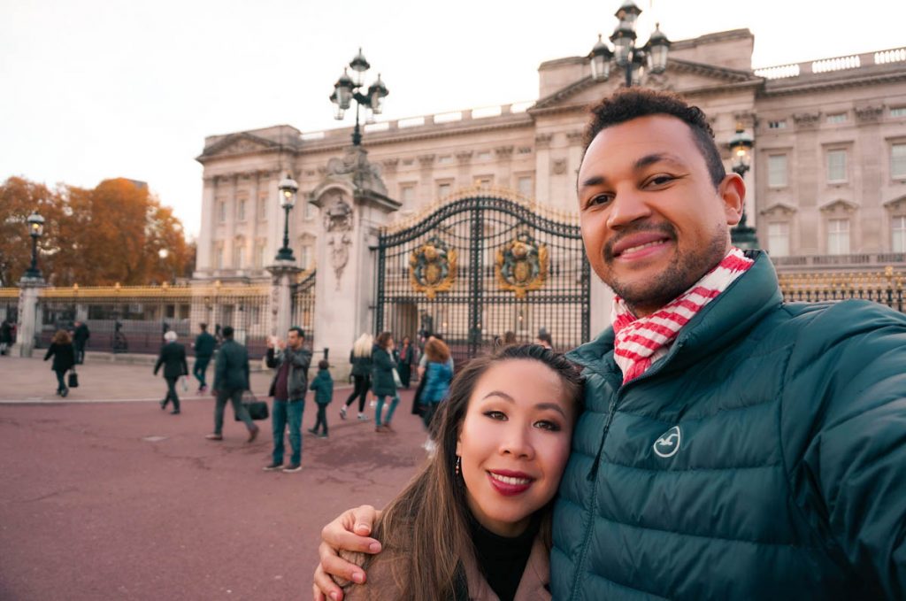 a couple taking a selfie in front of buckingham palace whilst living in london