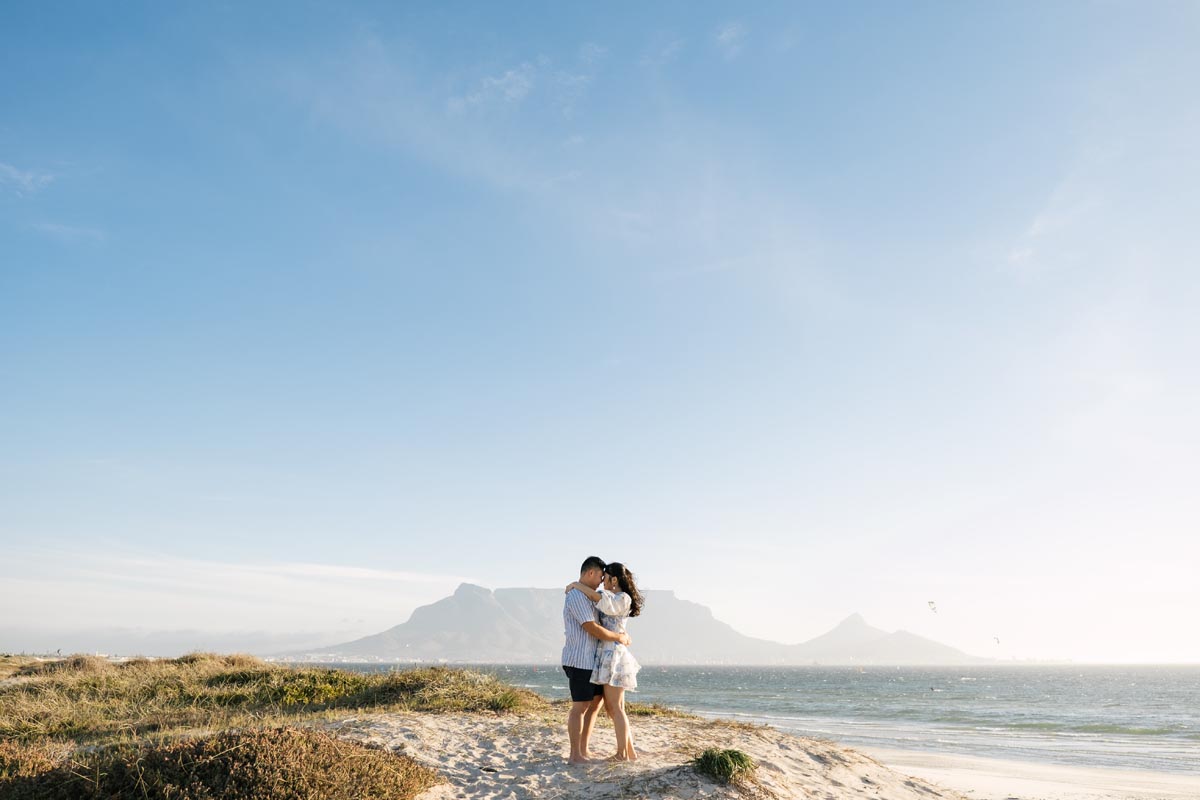 a couple photoshoot at sunset beach with the silhouette of table mountain in the background