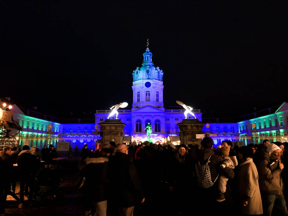 a view of charlottenburg palace christmas market in berlin with the palace let in blue and green lights