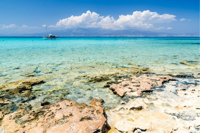 clear, turquoise blue waters from chrissi beach on chrissi island in south crete greece with flat top corals and a view of a ferry boat