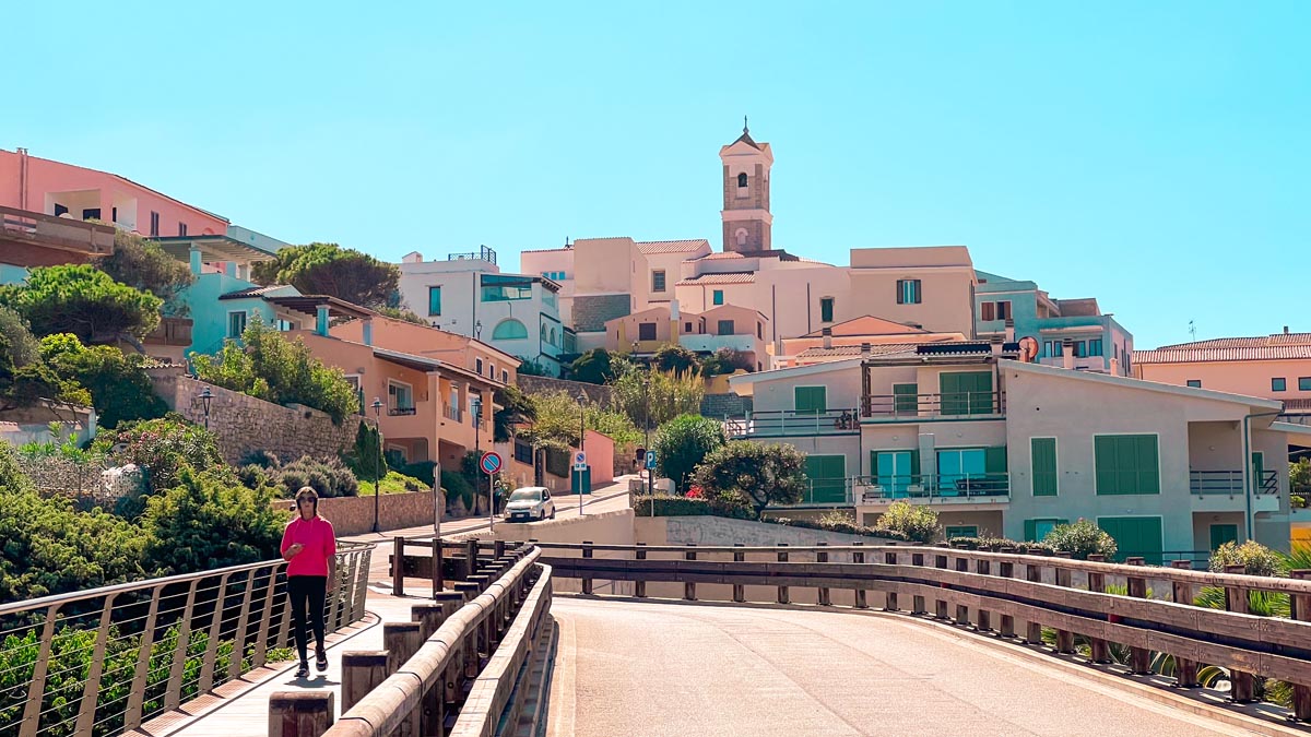 a woman walks on the sidewalk in santa teresa gallura, a city shown in the farthest north in Sardinia