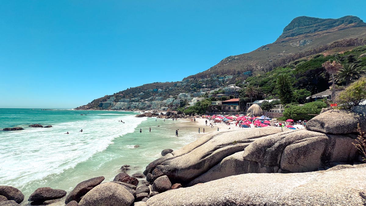 a view of clifton beach with red umbrella locals and tourists on the beach on a hot sunny day