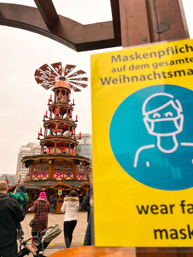 a sign with covid rules at the entrance of a christmas market in germany