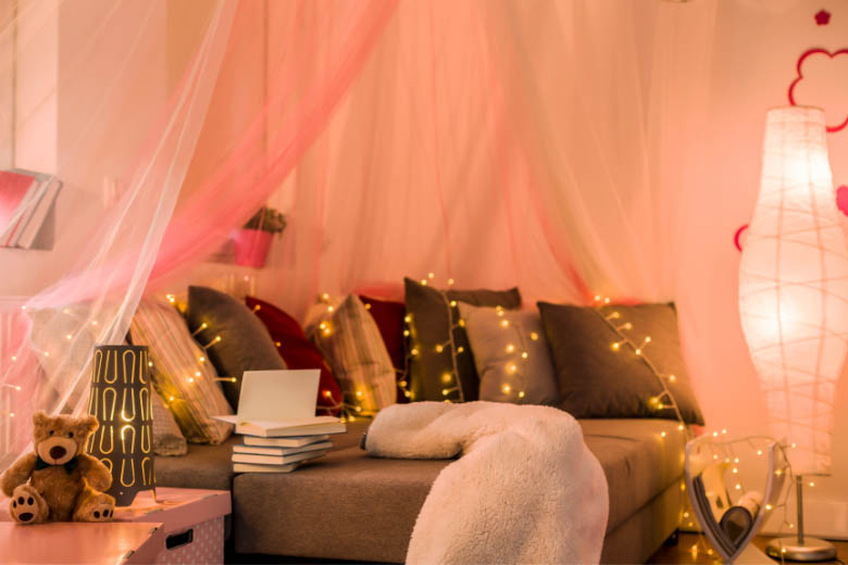 a cosy sofa in a living room with soft curtains, rug and fairylights during winter in germany