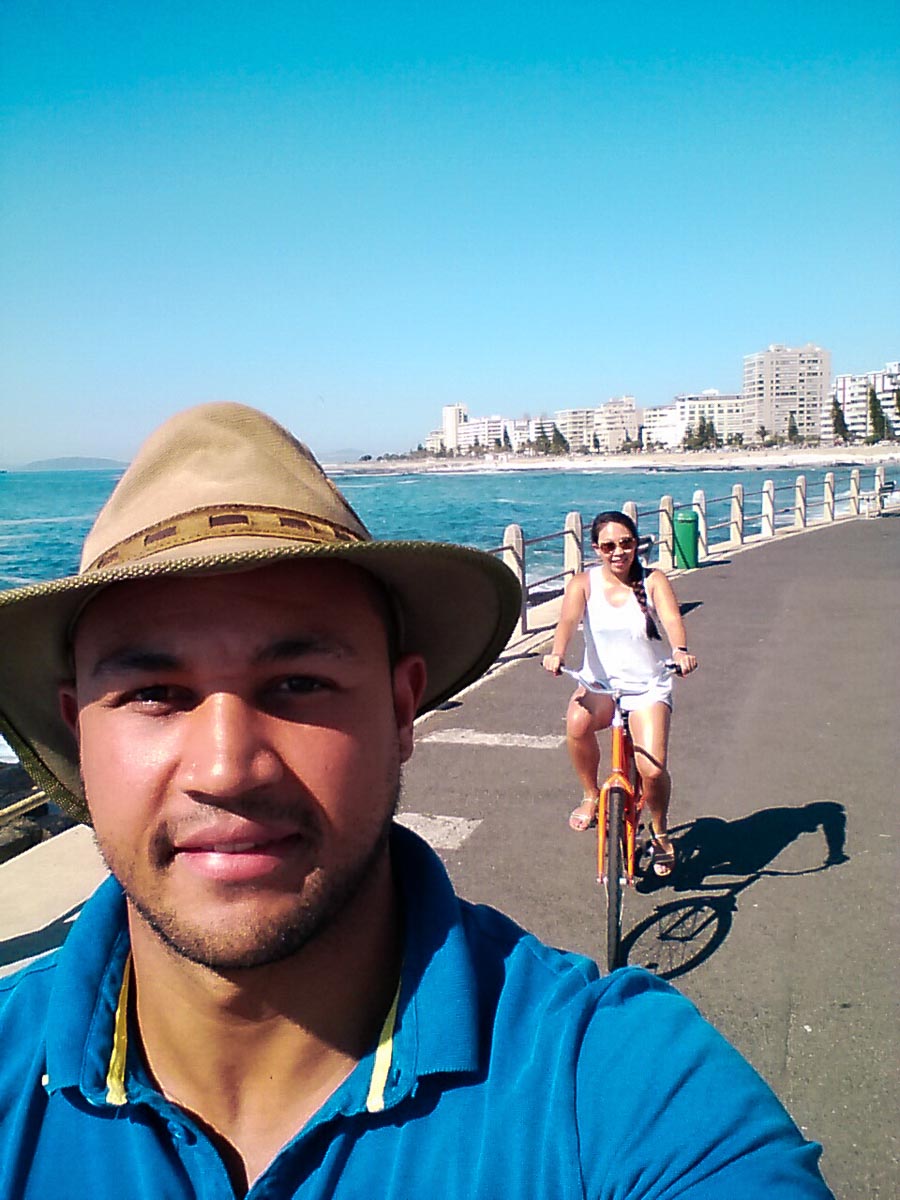 a man taking a selfie whilst cycling along sea point promenade whilst on honeymoon