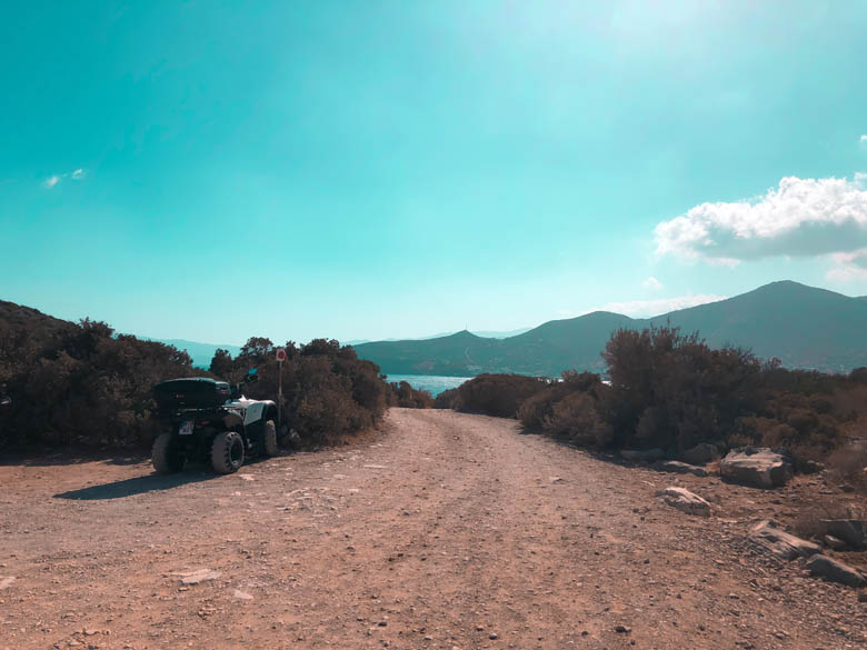 an unpaved dirt path in crete greece with a view of the ocean and mountains ahead