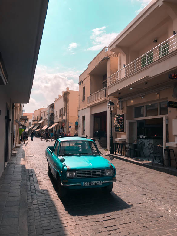 a old blue classic car driving in the streets of old town chania crete 