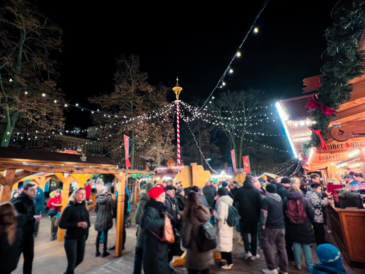 locals gather around festive wooden stalls buying traditional german christmas food like gluhwein and bratwurst in zehlendorf