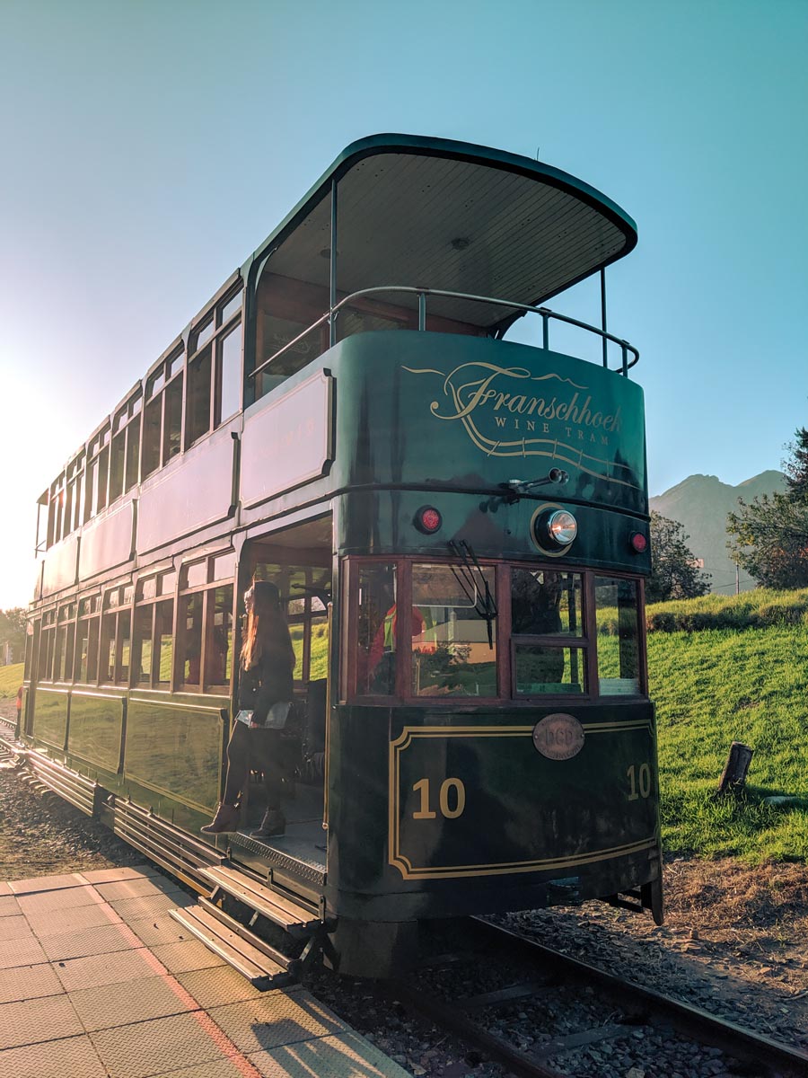 the emerald green double deck franschhoek wine tram taking tourists on different wine tasting itineraries