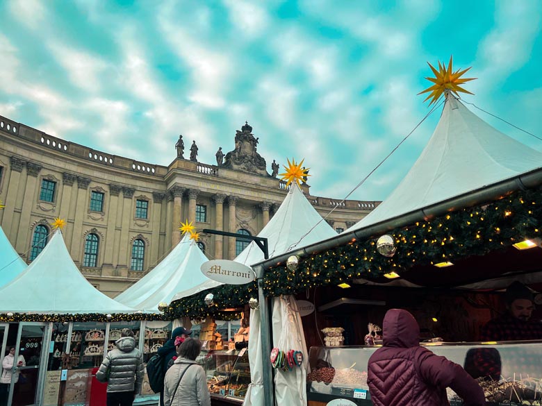 white christmas market tents sheltering food stalls in front of humboldt university in berlin