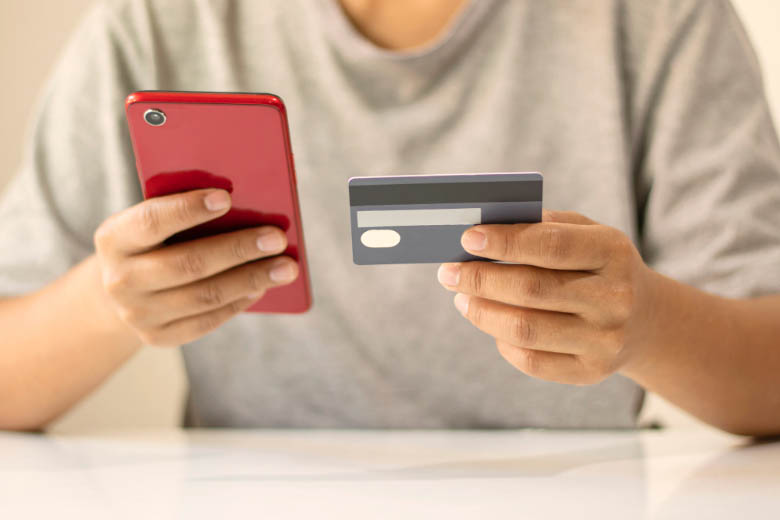 a person holding a mobile phone and a bank card 