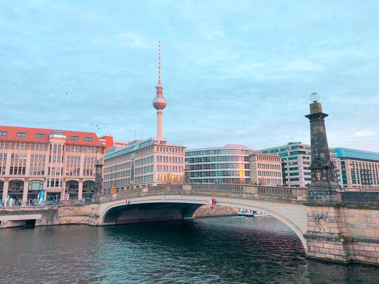 a view of a bridge connecting downtown berlin to museum island with the tv tower in the backdrop