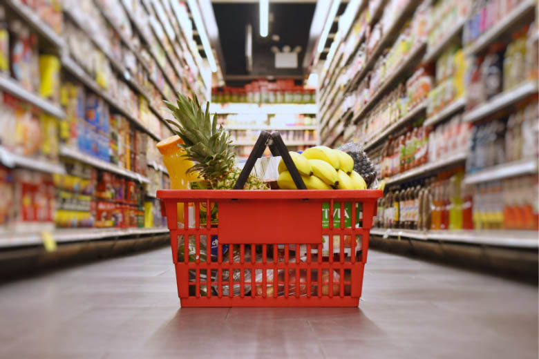 a red basket full of food and groceries lying in the middle of an aisle in a German supermarket