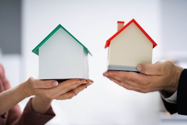 two people holding house models in their hands