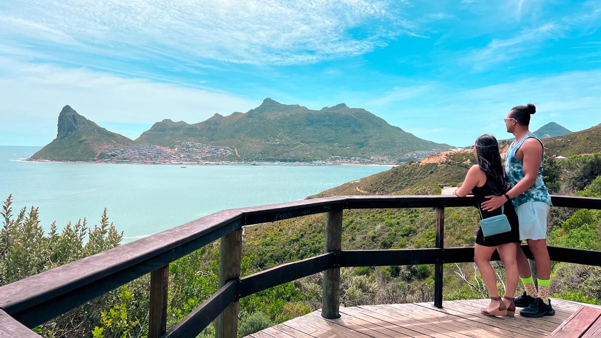 a couple standing on a wooden viewing deck along chapman's peak drive in kapstadt sudafrika