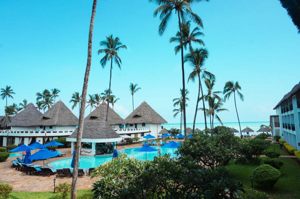 all inclusive beach resort on the beach in zanzibar with a swimming pool and tall palm trees