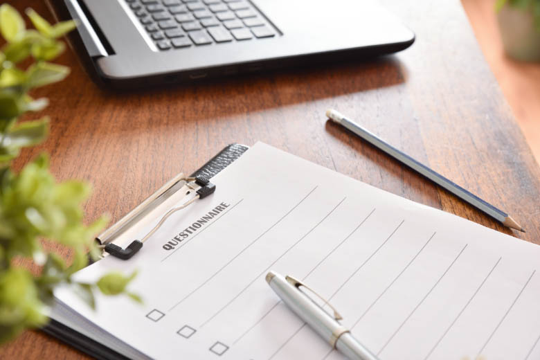 a questionnaire clipped to a board on a brown work desk with a pencil lying nearby