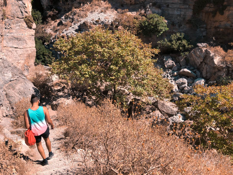 a man hiking down the steps to reach the bottom of the canyon at kourtaliotiko gorge