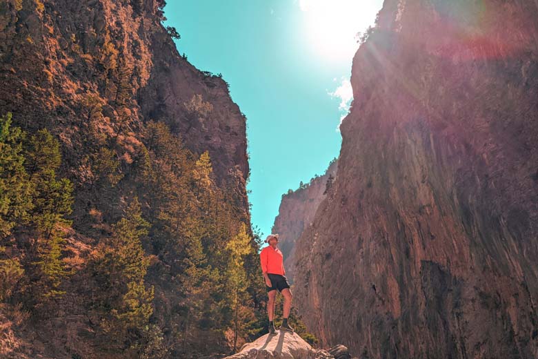 a man standing on a rock looking upwards on the samaria gorge hiking trail in crete greece