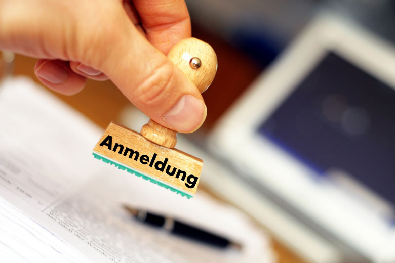 a person in germany holding a stamp with the word anmeldung on 