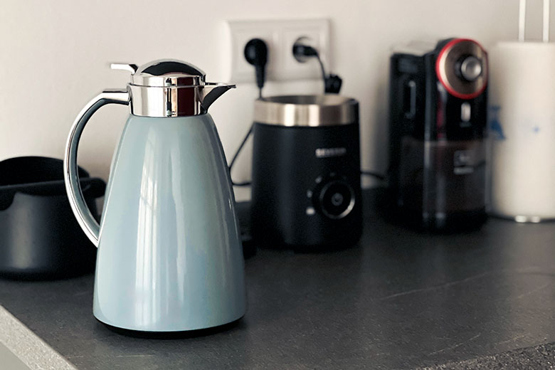 a pastel light blue emsa thermal flask sitting on a kitchen countertop next to other home appliances