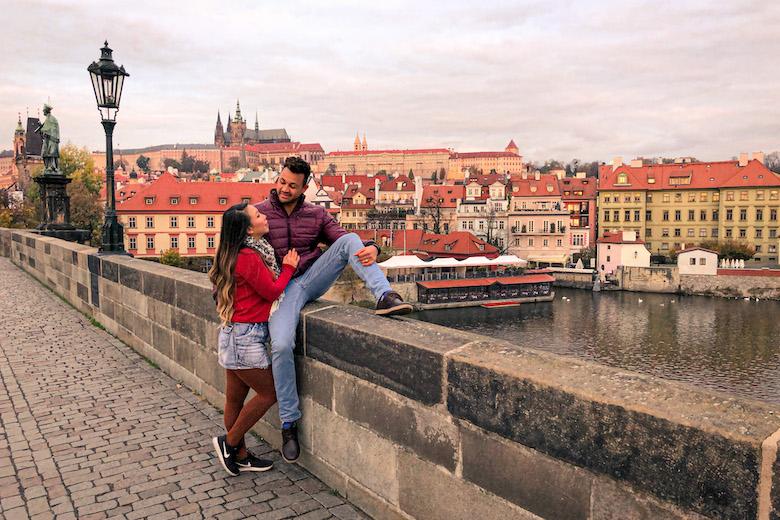 a couple sitting on charles bridge in prague