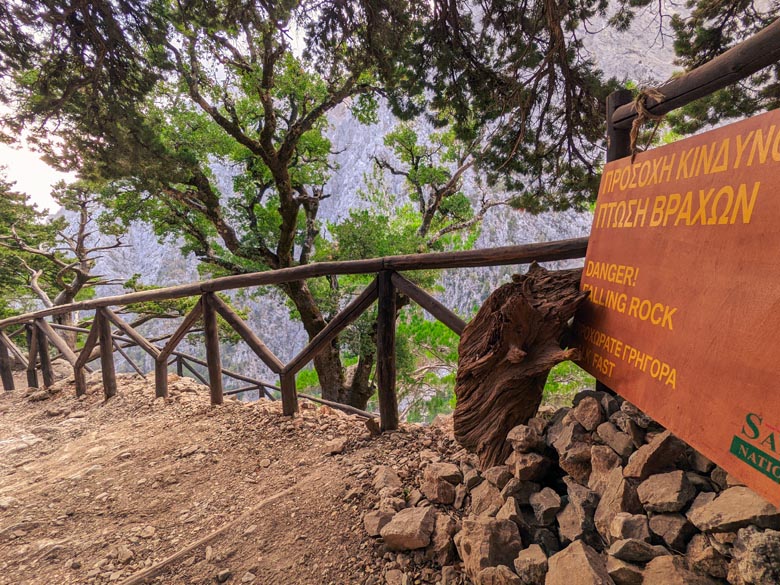 a sign warning hikers of danger of falling rocks on the samaria gorge hiking trail