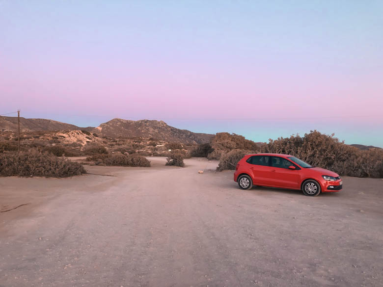 a red car hire parked on unpaved road in crete greece