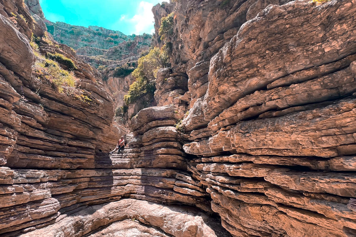 a man sitting at jacobs canyon in rhodes with stunning horizontal rock formations