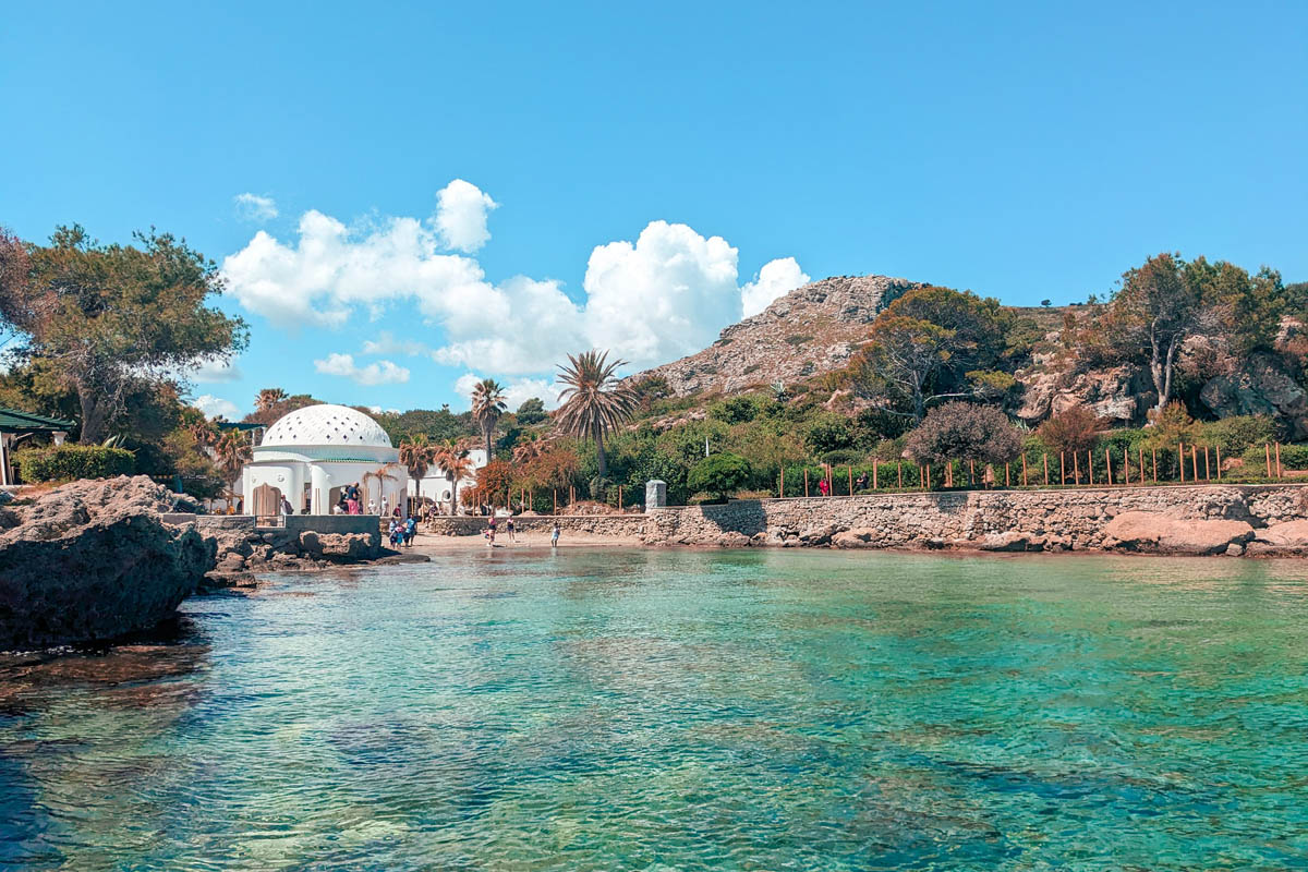 view of the beach at kallithea springs with white and blue architecture in the background 