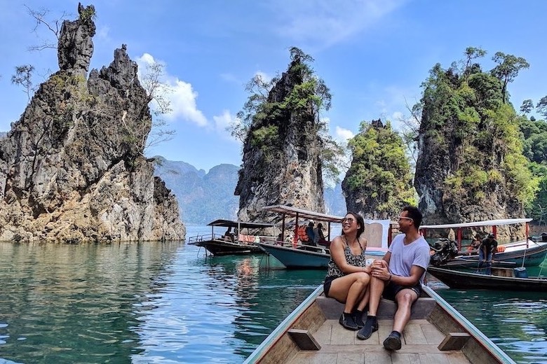 couple sitting on long tail boat on cheow lan lake in thailand